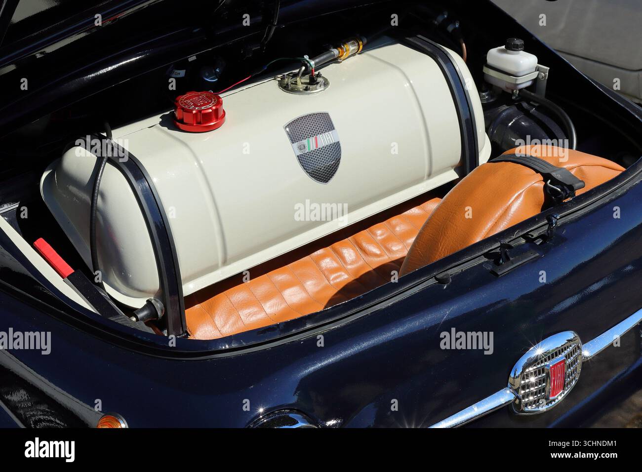 Questa foto ravvicinata mostra il vano motore posteriore di una Fiat 500 blu scuro. Il cofano posteriore è aperto, rivelando un grande serbatoio del carburante bianco personalizzato con logo a cresta. La vettura ha anche un sedile in pelle marrone e la classica griglia Fiat è parzialmente visibile. Illustrativo, editoriale: Lo Stokes Bay Car Rally a Gosport, Hampshire, Inghilterra. 25 agosto 2025. Foto Stock