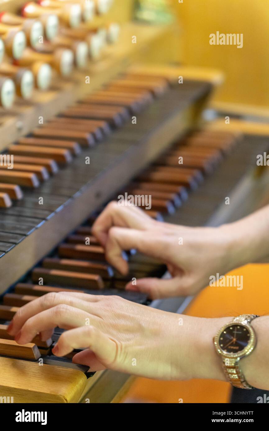 Una musicista suona un pezzo su un antico organo in legno in una tranquilla chiesa luterana, le sue mani si muovono con grazia attraverso le chiavi. Foto Stock