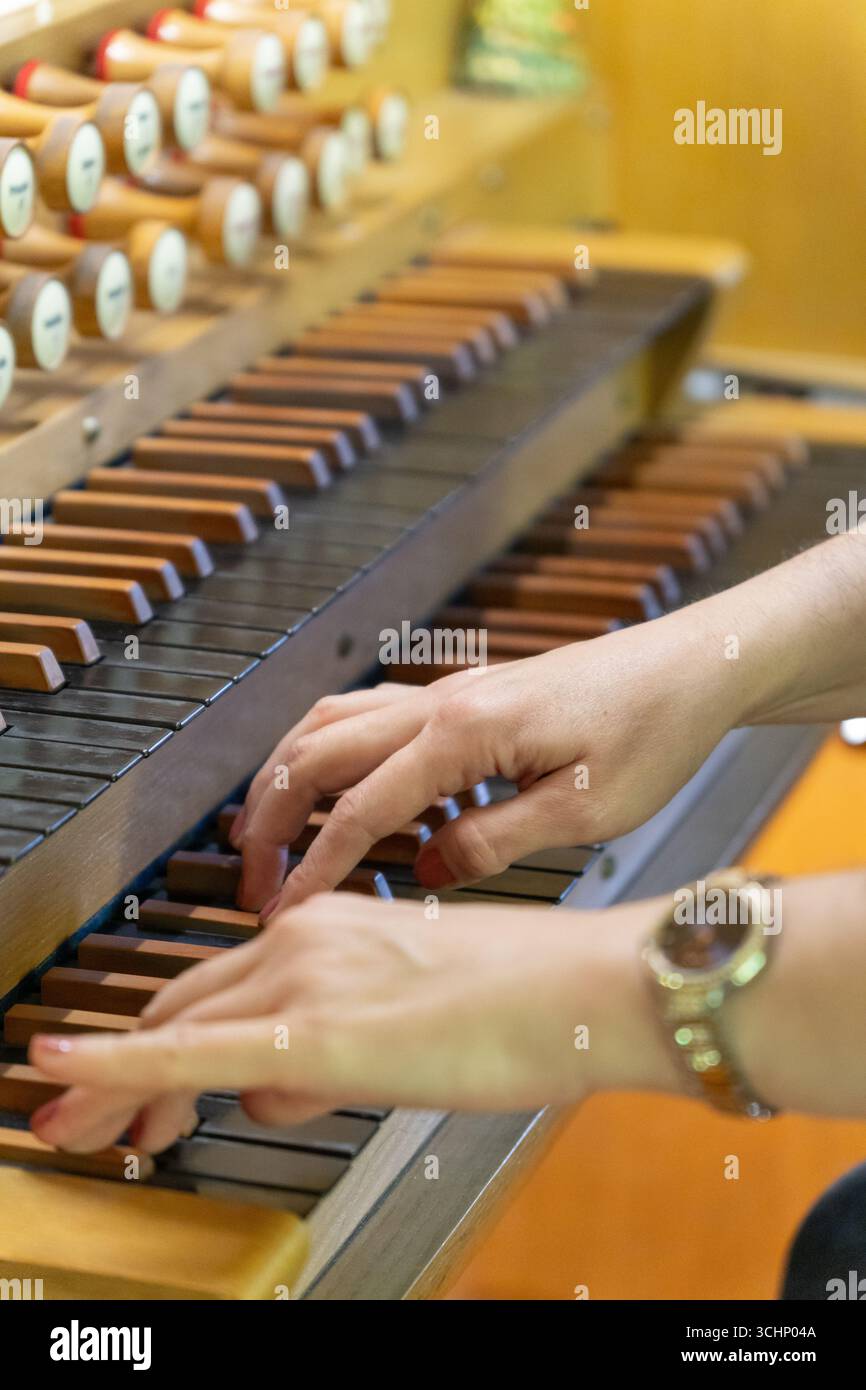 Una musicista suona un pezzo su un antico organo in legno in una tranquilla chiesa luterana, le sue mani si muovono con grazia attraverso le chiavi. Foto Stock