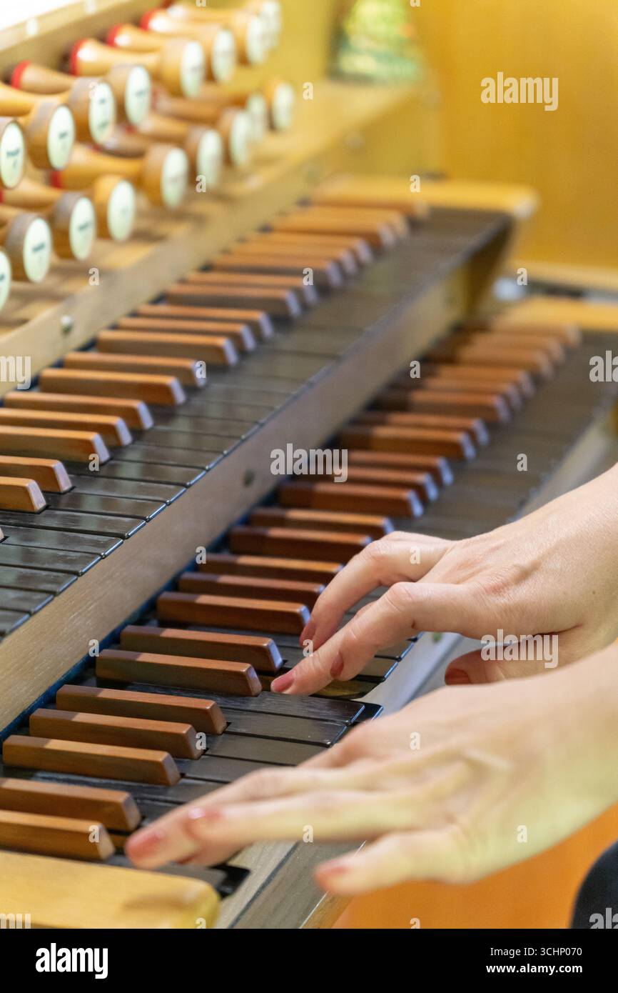 Una musicista suona un pezzo su un antico organo in legno in una tranquilla chiesa luterana, le sue mani si muovono con grazia attraverso le chiavi. Foto Stock