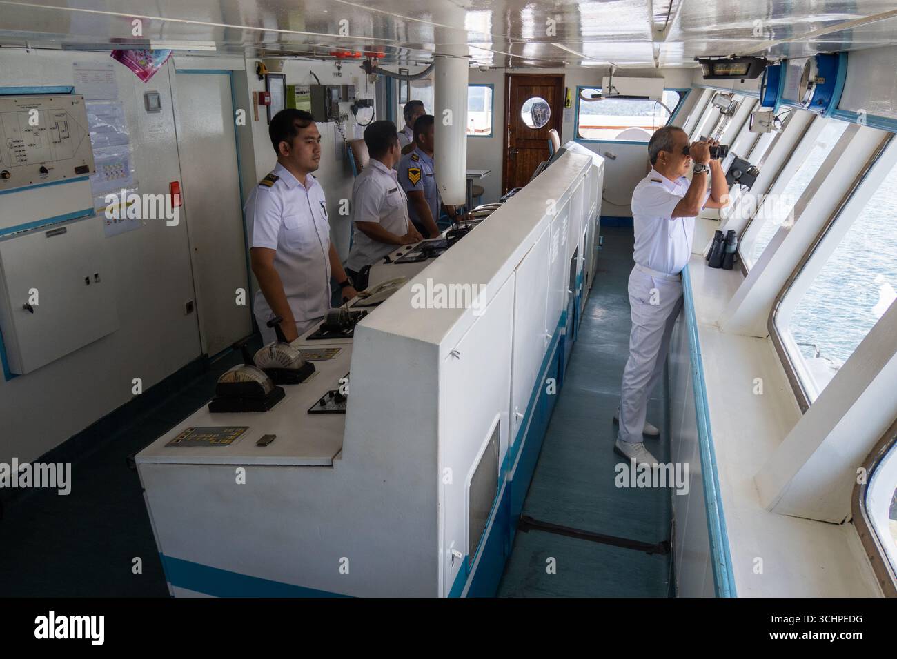 AMBON, INDONESIA - maggio 29: Il capitano guarda attraverso il binocolo. Gli ufficiali DELLA KM Pangrango guidarono la loro nave fuori dal porto di Ambon, Indonesia Foto Stock
