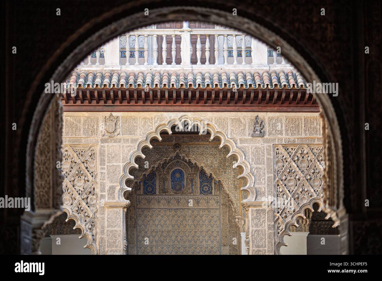 L'architettura Mudéjar mostra intricate incisioni intorno a un tranquillo cortile dell'Alcazar reale di Siviglia, immerso nella storia. Foto Stock