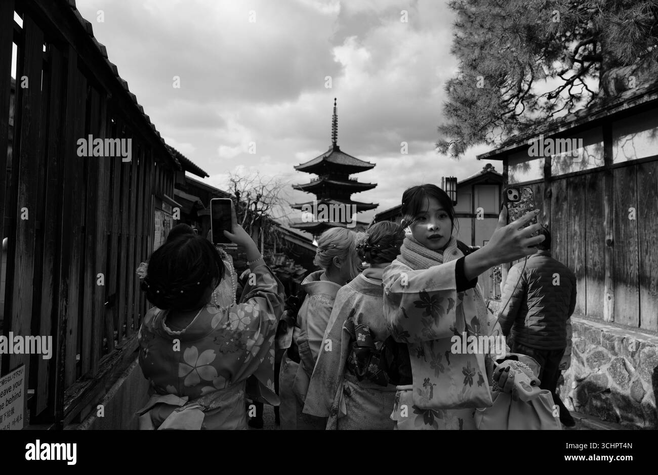 Le donne in kimono scattano selfie nella Higashiyama di Kyoto con la Pagoda Yasaka alta sullo sfondo, catturata in monocromia Foto Stock