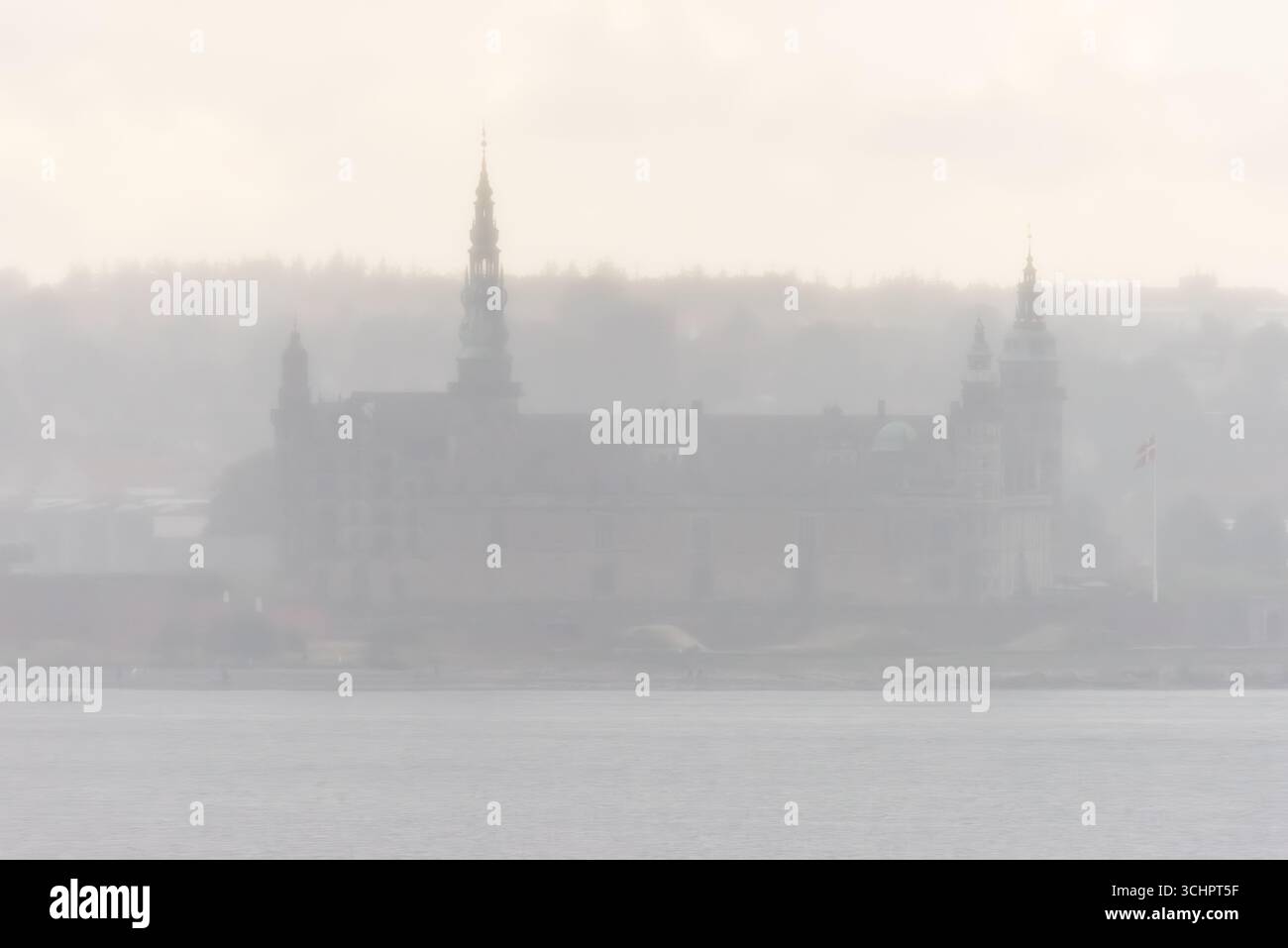 Castello di Kronborg attraverso Fog Helsingør Danimarca // Helsingør, Danimarca - Castello di Kronborg, patrimonio dell'umanità dell'UNESCO, è visibile attraverso una fitta nebbia. Il castello del XV secolo, situato sull'isola di Zelanda, è visibile attraverso lo stretto di Øresund da Helsingborg in Svezia. Famoso come l'ambientazione del borgo di William Shakespeare, la posizione strategica del castello di Kronborg nel punto più stretto del Øresund influenzò significativamente la storia danese e il commercio marittimo. Foto Stock