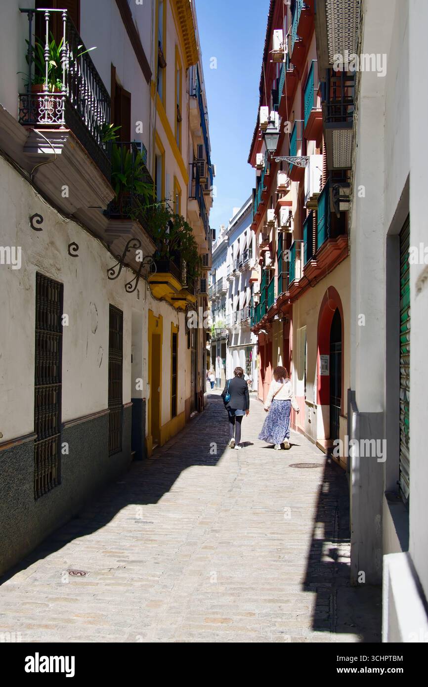 Architettura tipica in una strada stretta con turisti nel centro storico della città Siviglia Andalusia Spagna Europa Foto Stock