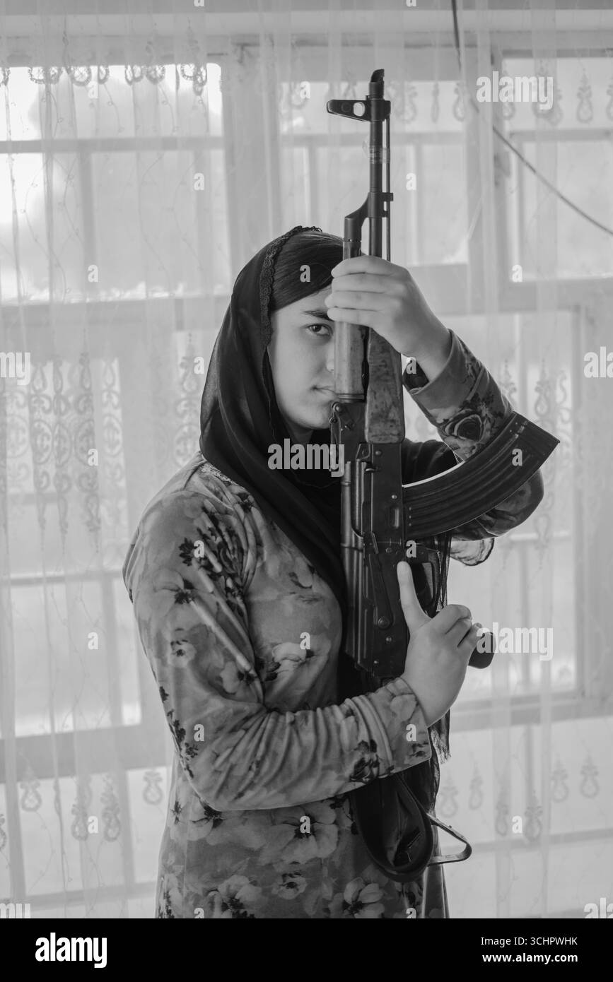 Le donne curde simboleggiano coraggio e resistenza, vitali nelle lotte politiche e civili. In Kurdistan, le case spesso tengono pistole, riflettendo la cultura, strug Foto Stock