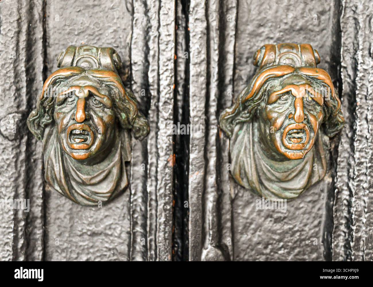 Un paio di maniglie delle portiere con volti umani scolpiti, con un'espressione affrancata o urlante, con bocche aperte e sopracciglia a solco, Venezia, Italia Foto Stock