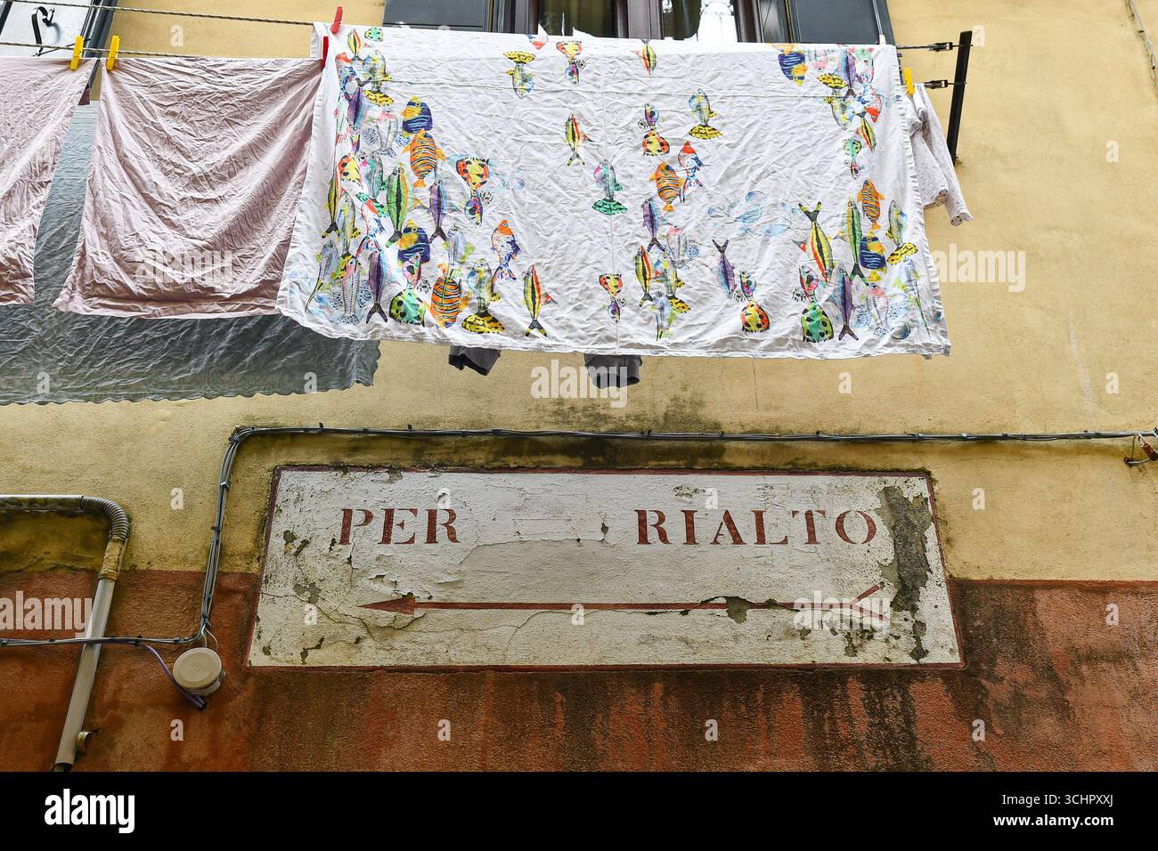 Primo piano della facciata di una vecchia casa con linee di lavanderia e un cartello con la scritta "a Rialto", Venezia, Veneto, Italia Foto Stock