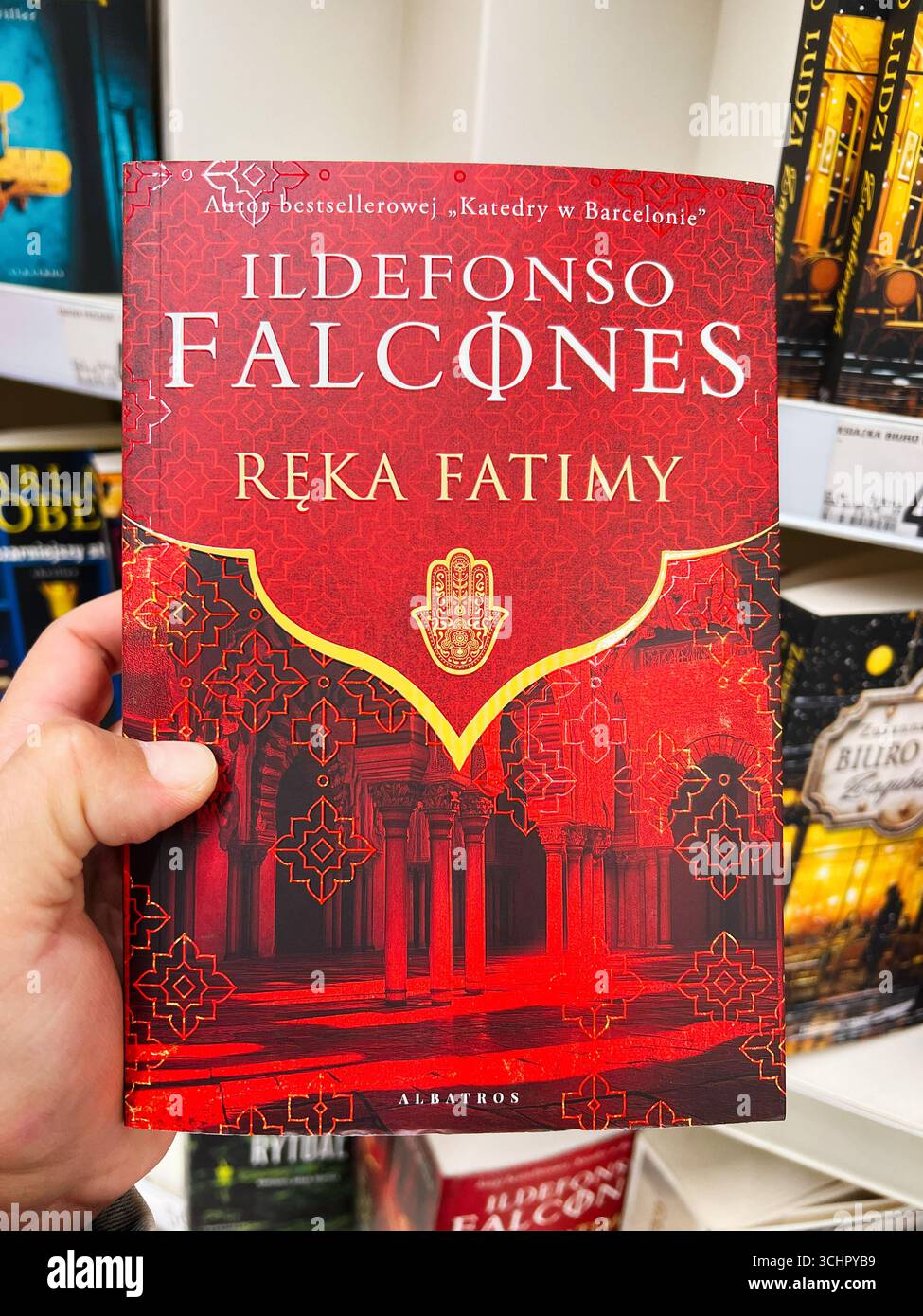 Rzeszow, Polonia - 22 agosto 2025: Copertina di un libro rosso brillante che mostra eleganti disegni in oro e un titolo di spicco. La mano di Fatima di Ildefonso Falco Foto Stock