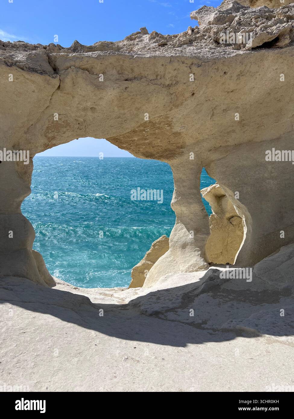 Una vista ravvicinata di un arco di roccia naturale sullo sfondo dello scintillante mare turchese. Foto Stock