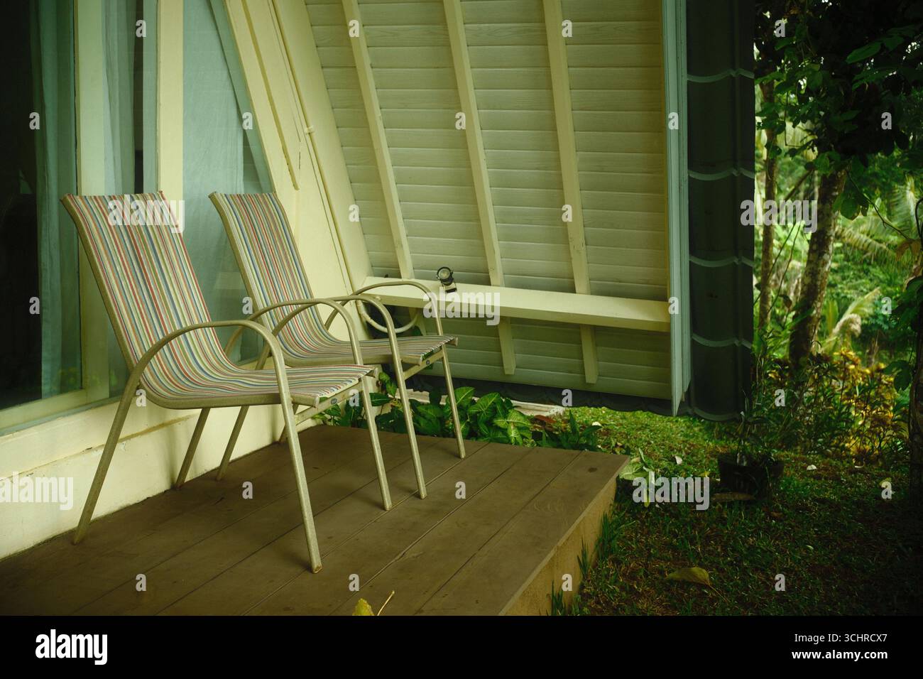 Sedie da patio su un portico di legno all'esterno di una moderna cabina con una parete inclinata nel giardino sul retro Foto Stock