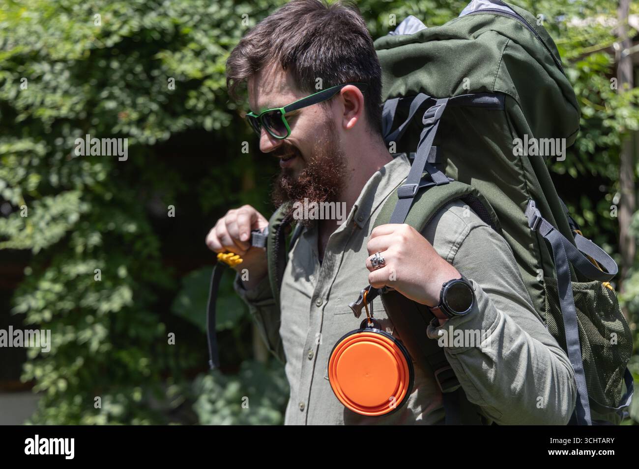 Vista dettagliata di uno zaino da trekking con una ciotola d'acqua per un cane. Rappresenta libertà, responsabilità e viaggi preparati con gli animali domestici. Foto Stock