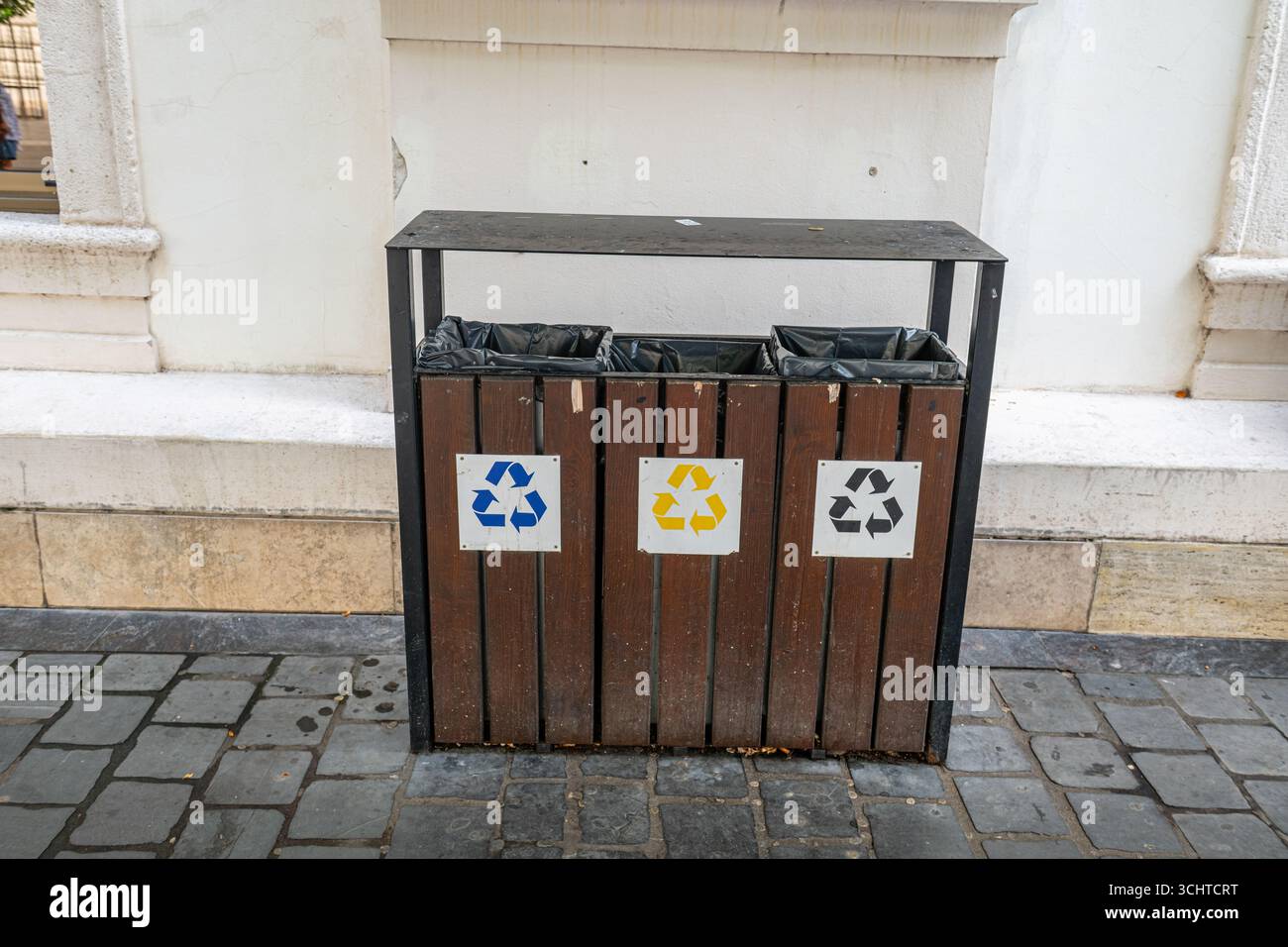Cestini per spazzatura in legno e una stazione di riciclaggio all'aperto dotata di simboli codificati per colore. Foto Stock