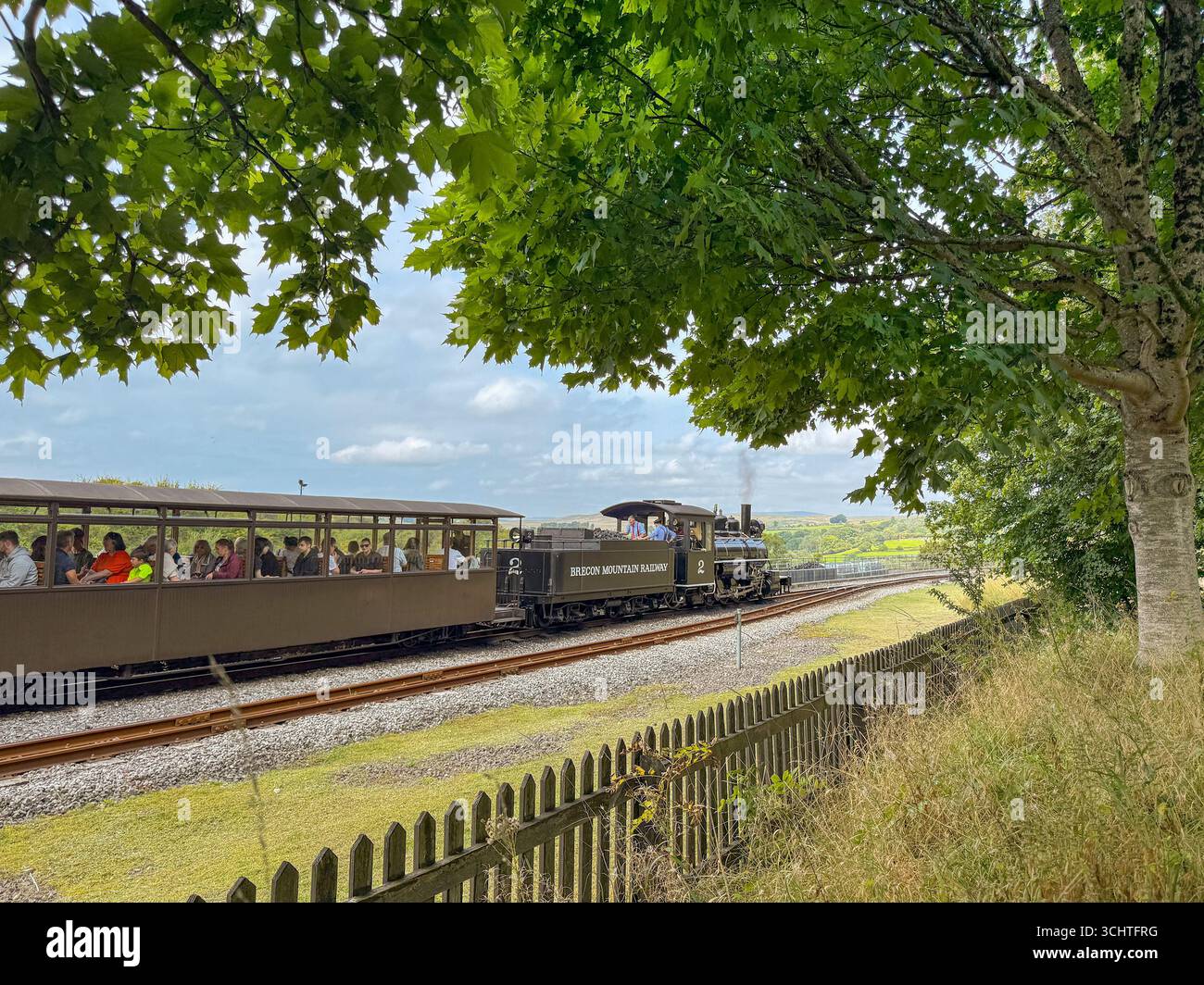 Merthyr Tydfil, galles, Regno Unito - 19 agosto 2025: Treno a vapore vintage a scartamento ridotto con passeggeri in partenza dalla stazione di Pant sulla Brecon Mountain Railway - Immagine stock catturata con smartphone
