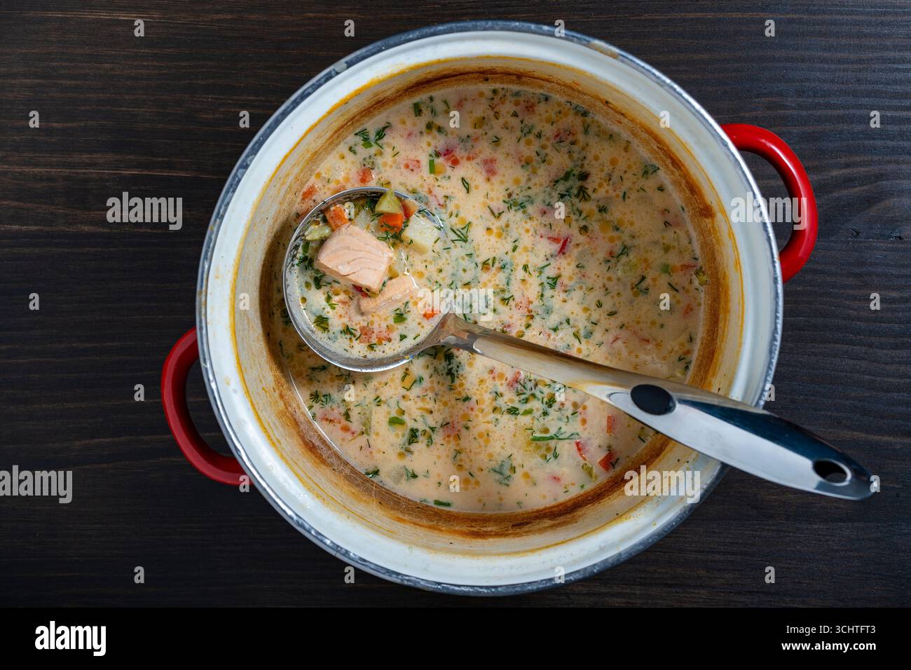 Gli avanzi della zuppa di pesce panna in una casseruola con mestolo su un tavolo di legno, primo piano, vista dall'alto Foto Stock
