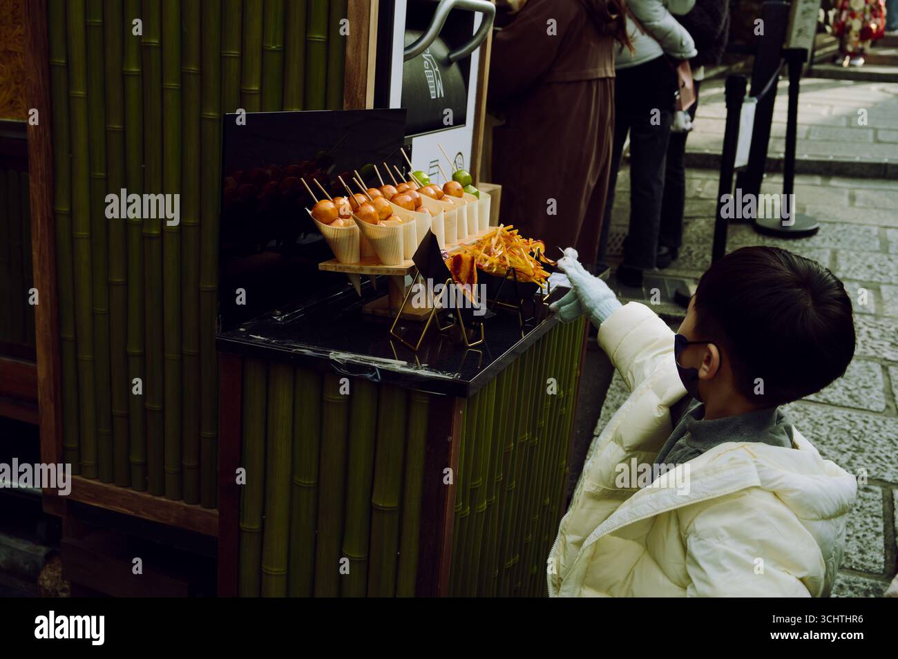 Un ragazzo curioso nel quartiere Higashiyama di Kyoto esamina la riproduzione di cibo di strada fuori da un piccolo ristorante Foto Stock
