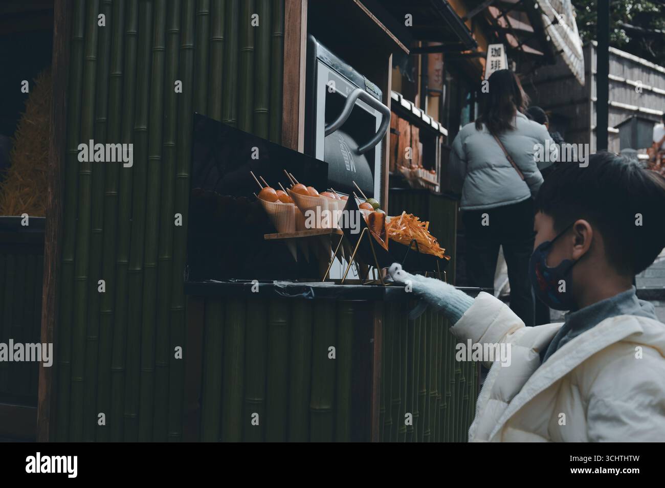 Un ragazzo curioso nel quartiere Higashiyama di Kyoto ammira una riproduzione di cibo di strada fuori da un piccolo ristorante Foto Stock