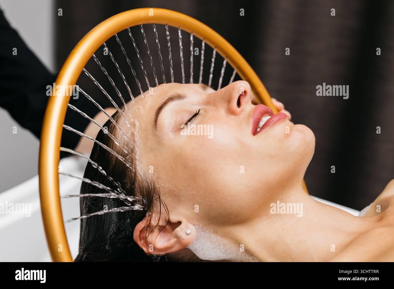 Donna che sperimenta la terapia con idromassaggio con acqua rilassante che scorre sopra la testa in un tranquillo ambiente spa, migliorando il relax e il benessere attraverso Foto Stock