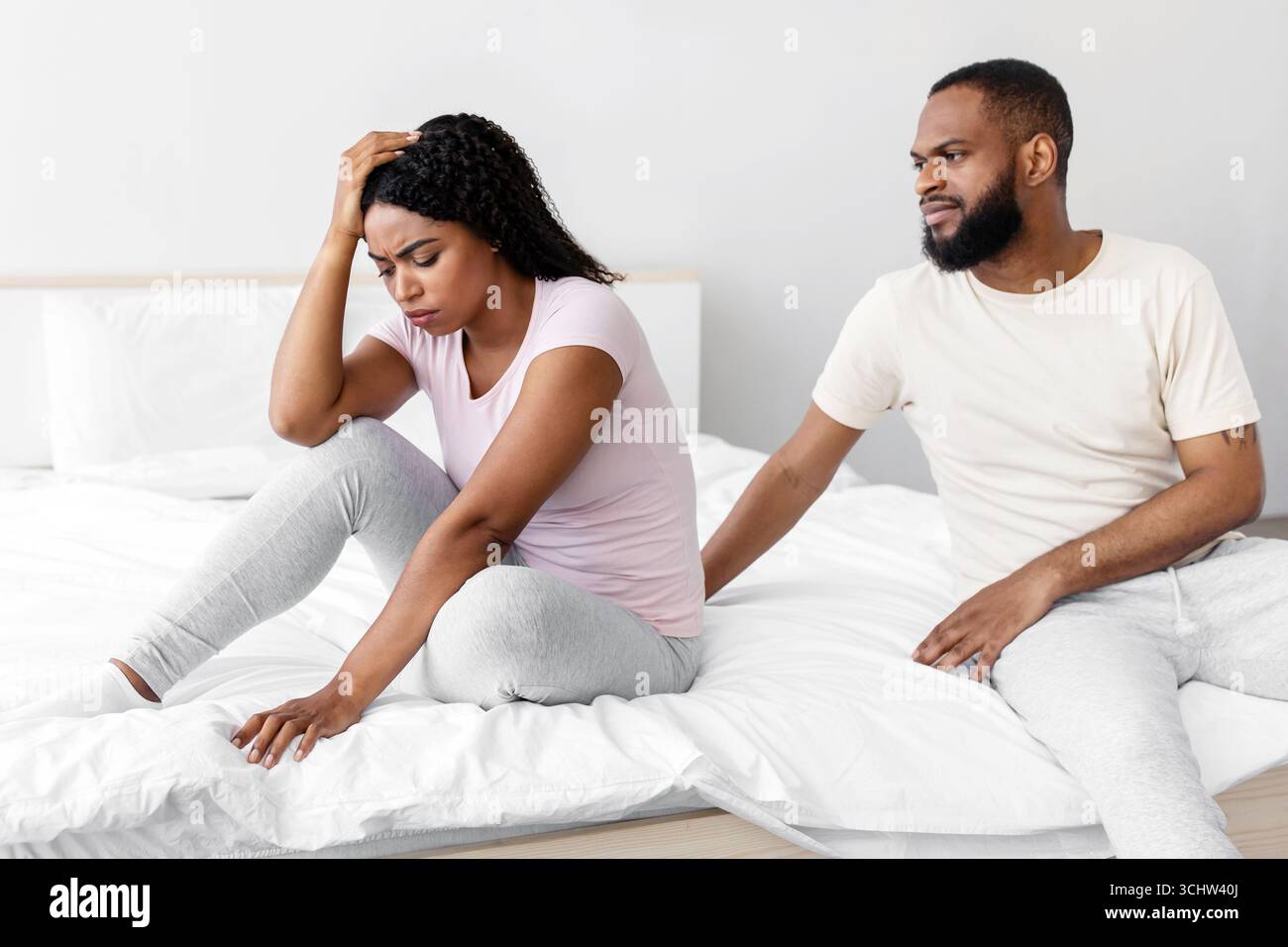 Serio giovane uomo nero calma a triste disperata moglie depressa, sedersi sul letto in camera da letto interno Foto Stock