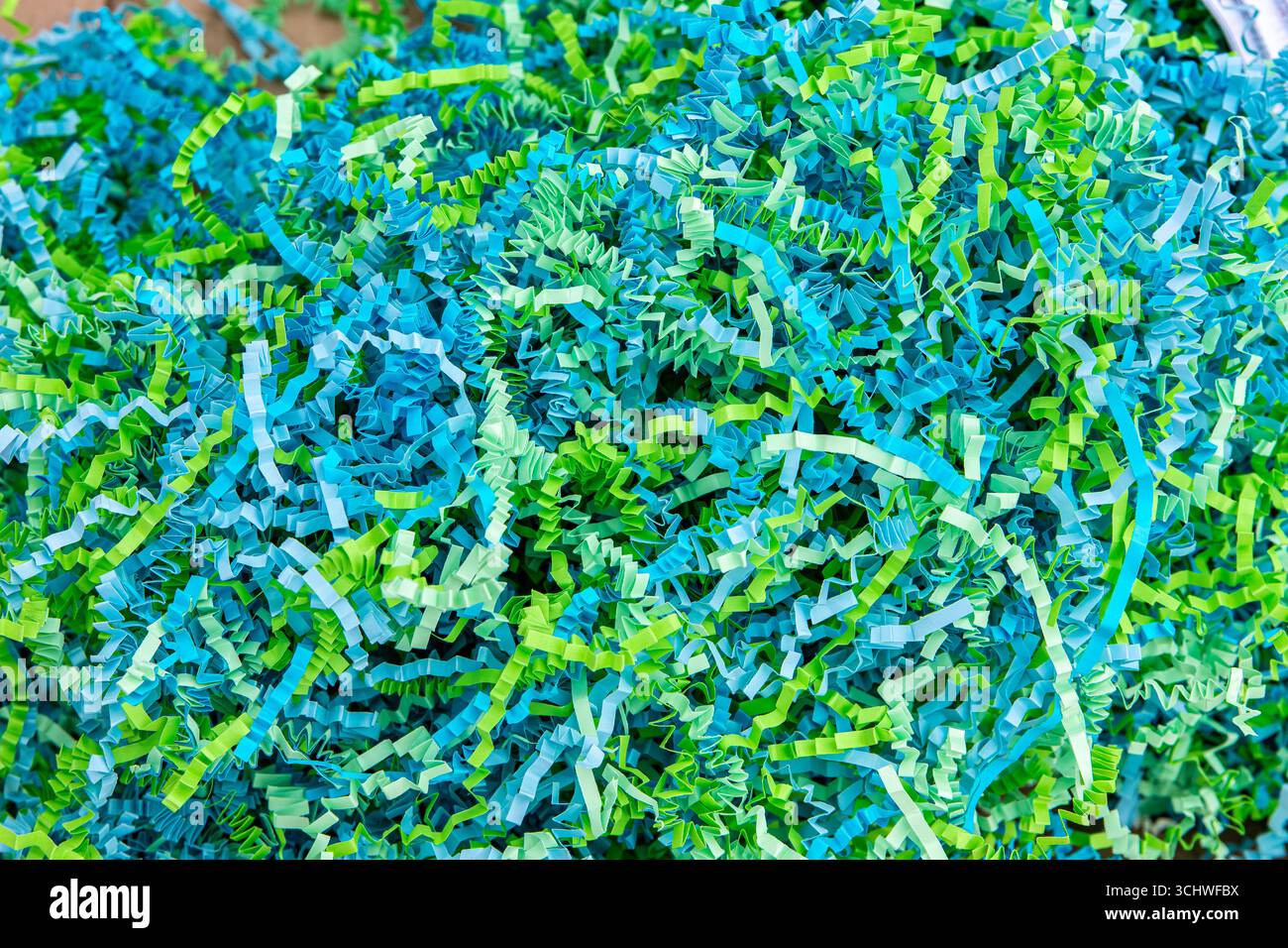 Primo piano di strisce di carta increspata blu e verde utilizzate come materiale di imballaggio protettivo per articoli fragili, con particolare attenzione alla consistenza Foto Stock
