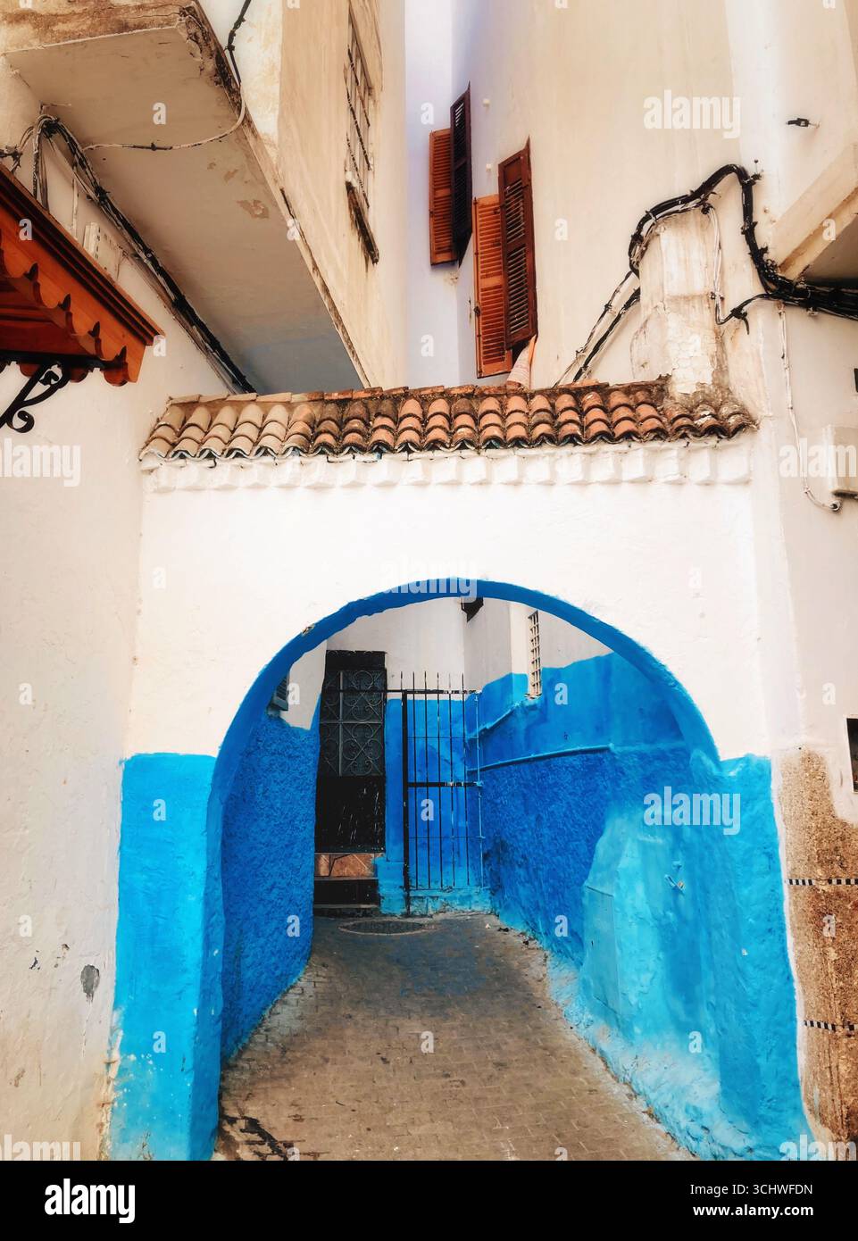 Vicolo illuminato dal sole nella Medina di Tangeri, pareti dipinte di blu e passaggi ad arco del patrimonio marocchino e fascino senza tempo. Agosto 16,2025 Foto Stock