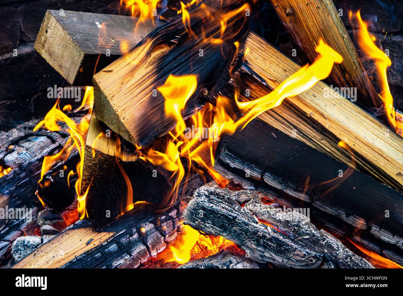 Un primo piano di legna e fiamme in fiamme, utilizzato per cucinare cibo e rimanere al caldo durante le avventure all'aperto, come il campeggio o le escursioni, ideale per sopravvivere Foto Stock