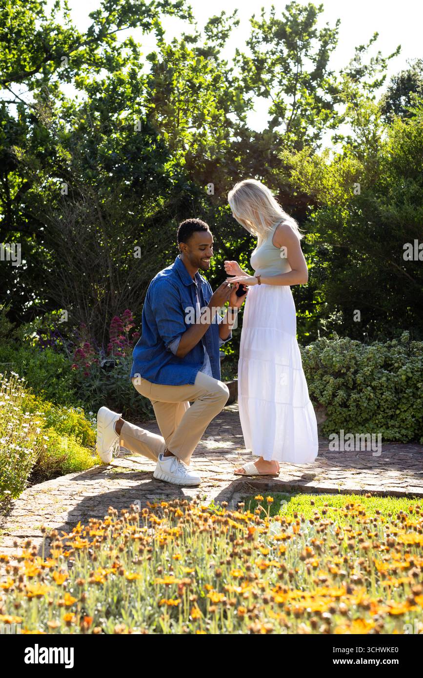 Uomo che si propone alla donna in giardino, sorridente e godendo di momenti romantici, copia spazio Foto Stock
