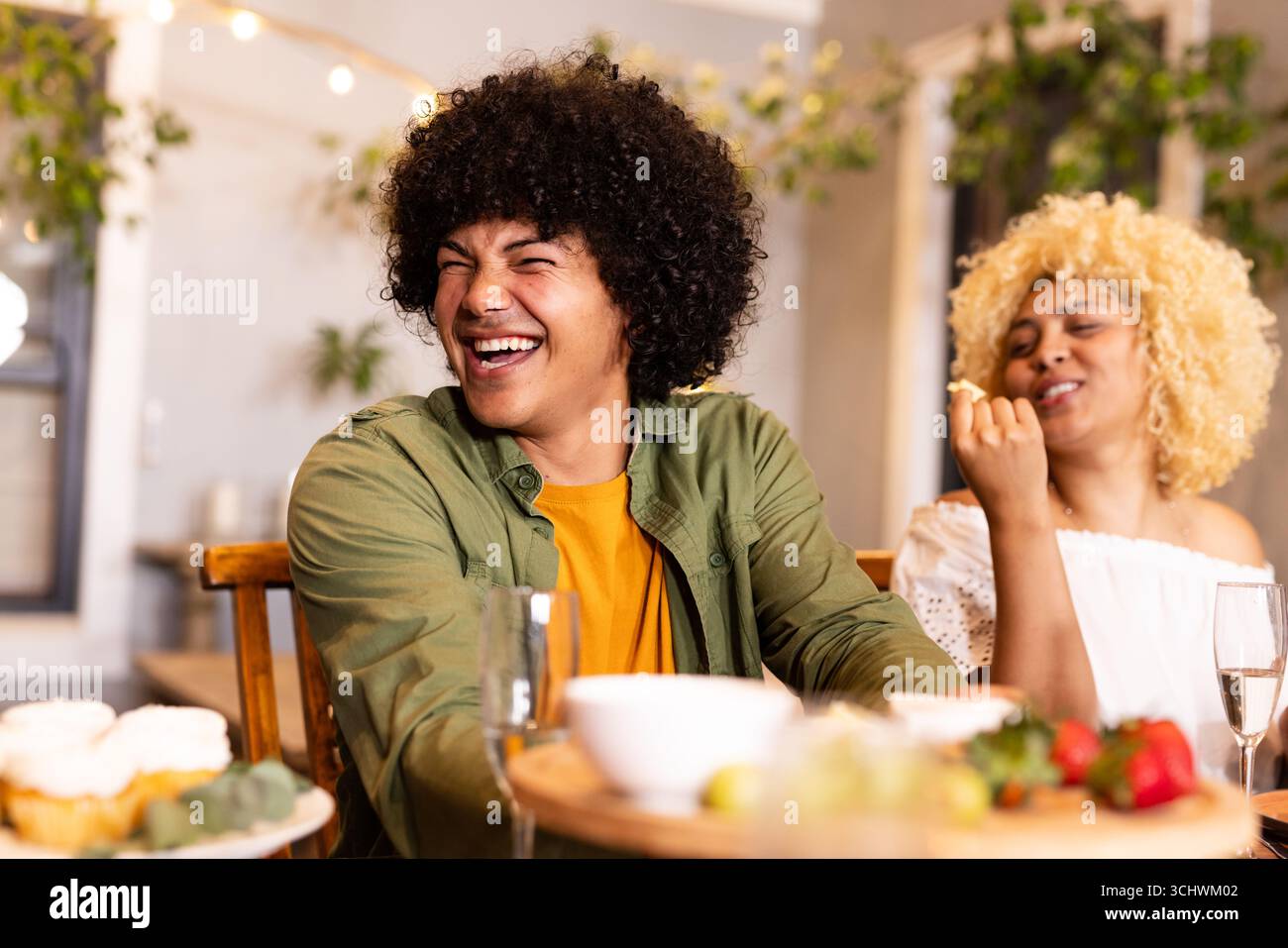 Amici diversi che ridono e si gustano spuntini in un'accogliente riunione di casa, si sentono felici, sul patio Foto Stock