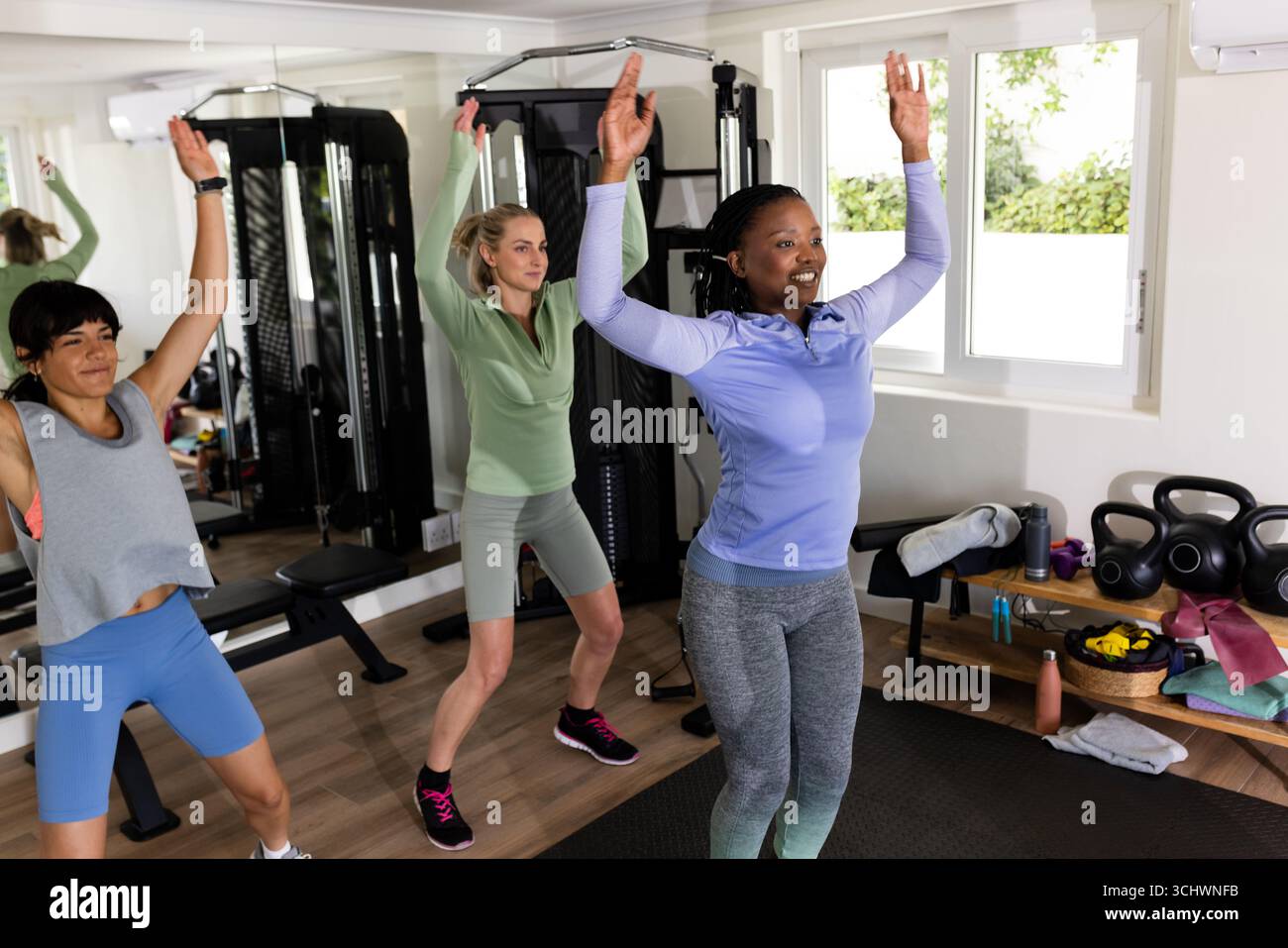 Donne che si allenano insieme in palestra domestica, sollevano le braccia e mantengono attiva la propria attività Foto Stock