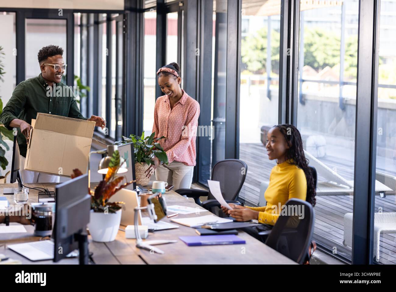Disimballaggio e condivisione di idee, colleghi afroamericani che collaborano in ufficio Foto Stock