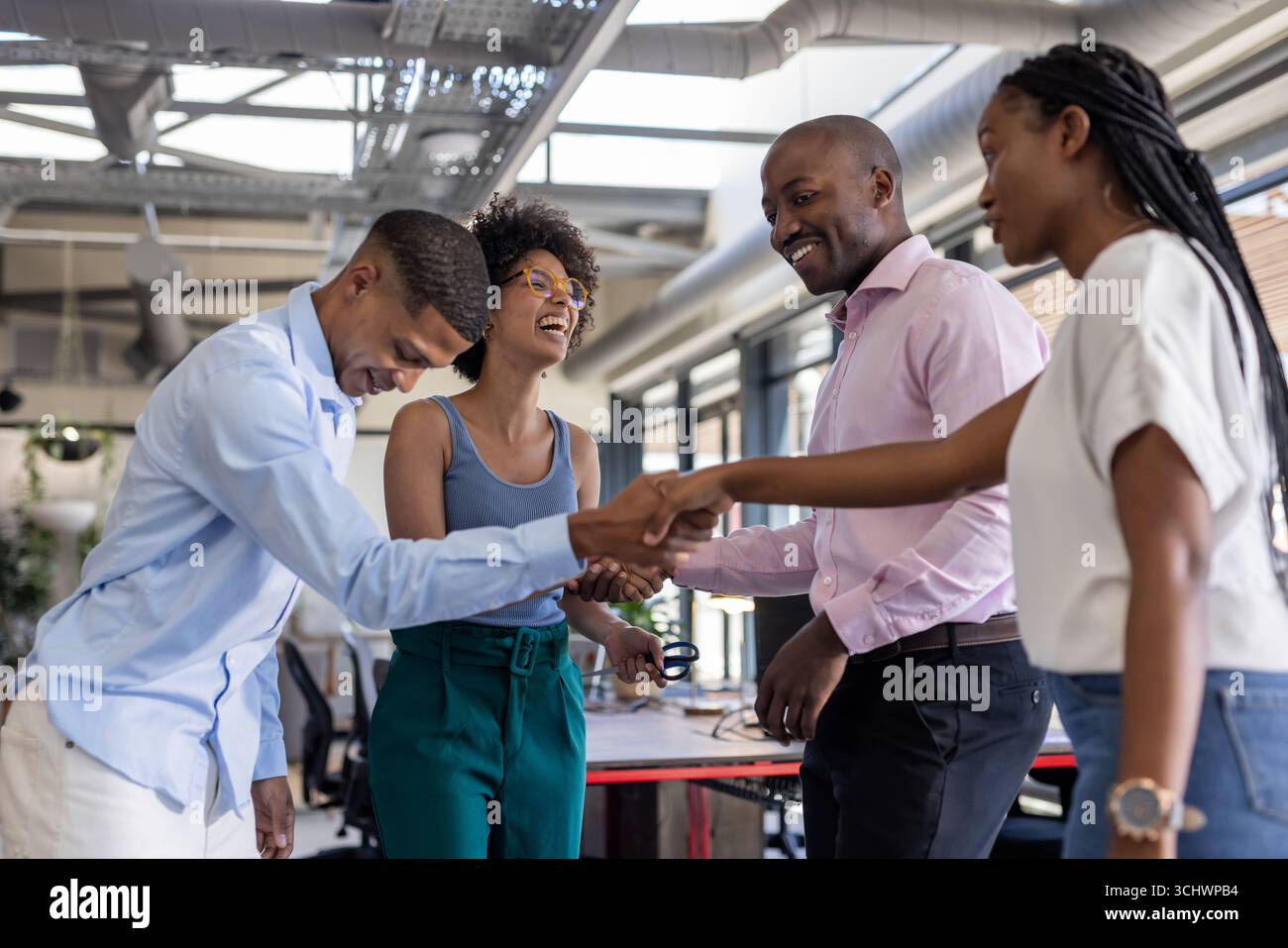 In ufficio, i colleghi stringono la mano, sorridono, celebrano il lavoro di squadra di successo insieme Foto Stock