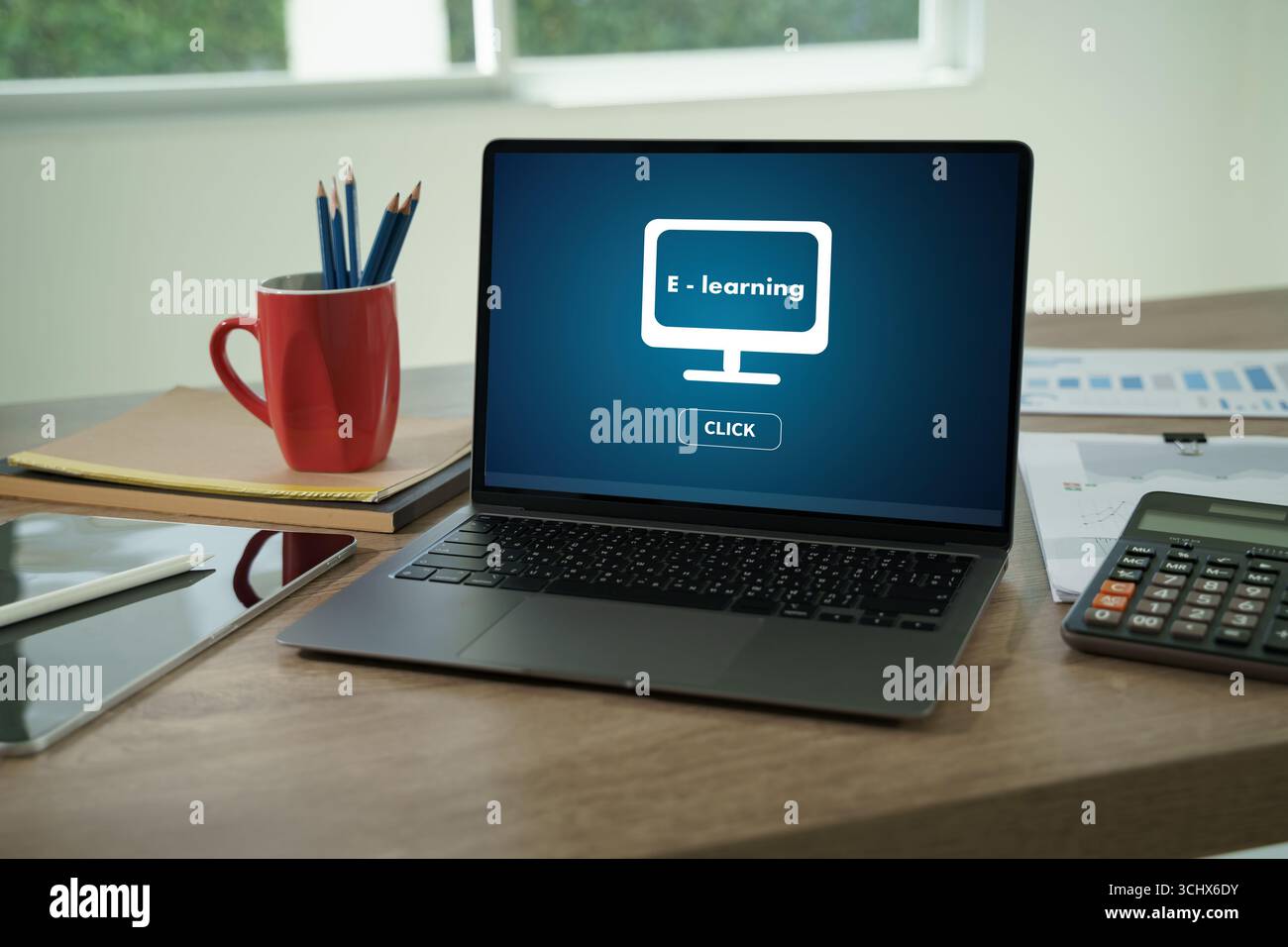 Schermo del notebook che mostra il concetto di e-learning sulla scrivania con tablet, calcolatrice e cancelleria, che rappresenta l'istruzione online, l'apprendimento digitale, e moderno Foto Stock