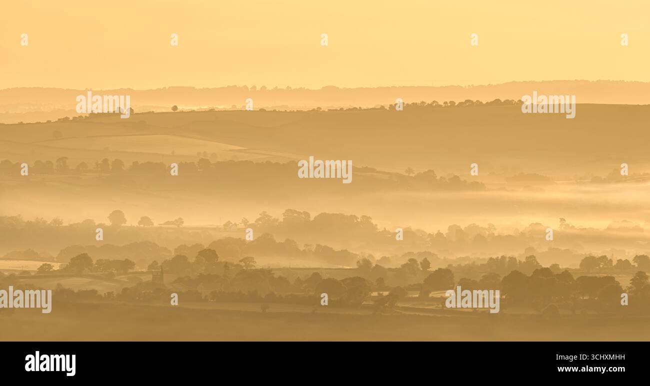 Strati di paesaggio nebbioso presi vicino a Blagdon, nel Somerset settentrionale all'alba, guardando verso Butcombe, parte delle Mendip Hills Foto Stock