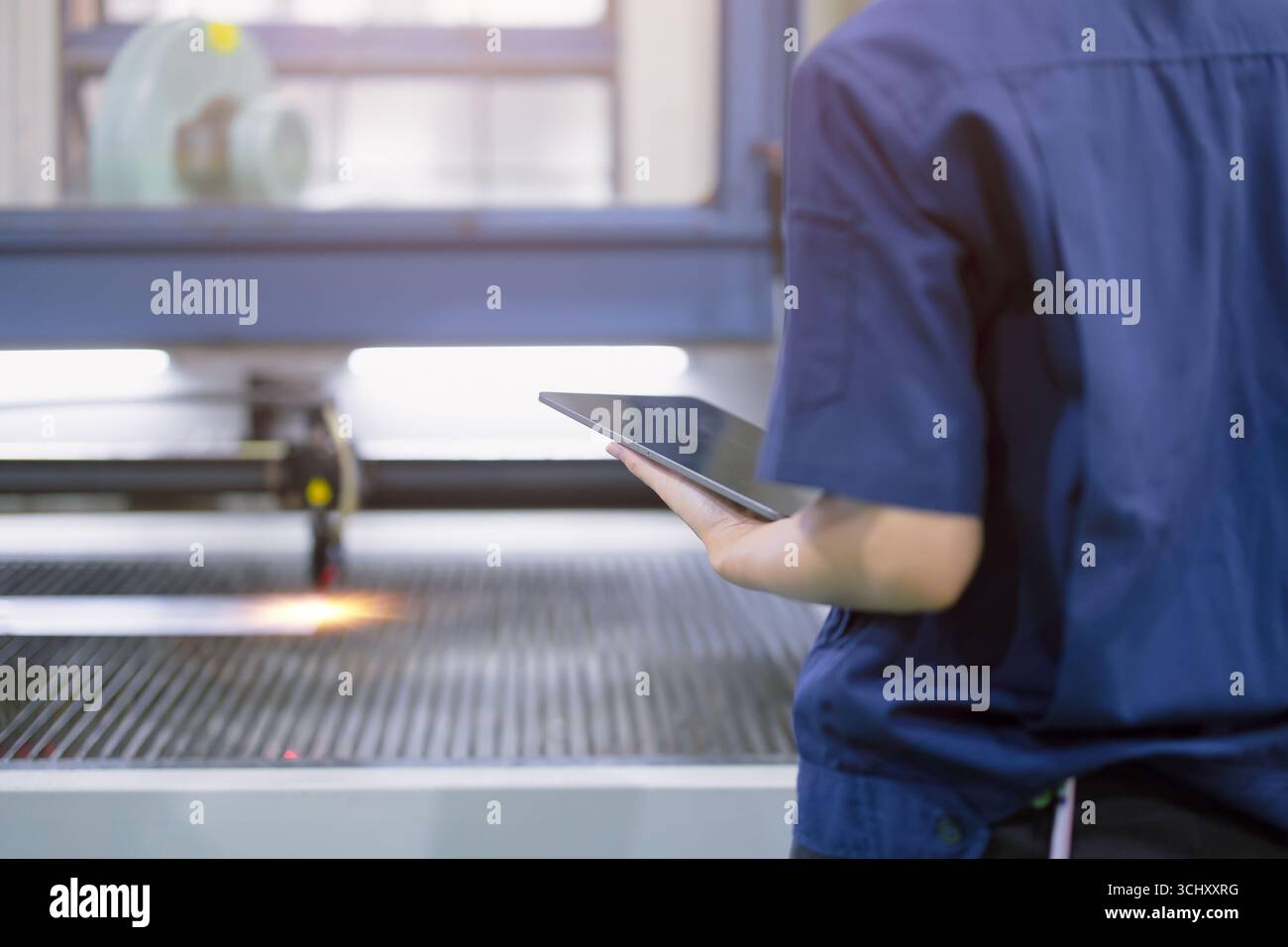 Tecnico ingegnere lavoratore controllo aziona la macchina da taglio laser in metallo nella moderna fabbrica dell'industria pesante dell'acciaio Foto Stock