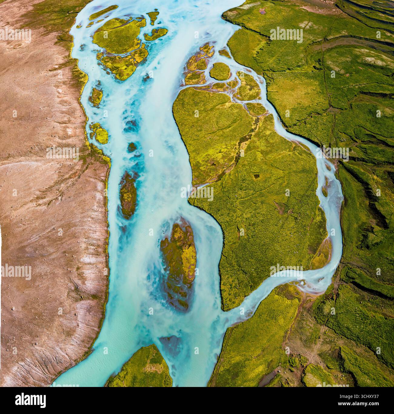 Vista aerea del fiume glaciale Hvita che serpeggia attraverso un paesaggio verde vivace, in contrasto con l'arida terra marrone, Bláskógabyggð, Islanda. Foto Stock