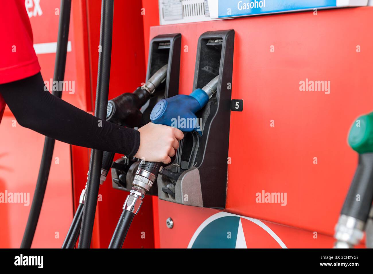 Primo piano operatore di una stazione di servizio che tiene a mano l'ugello del carburante per il rifornimento di carburante per auto, concetto di settore del mercato del petrolio Foto Stock