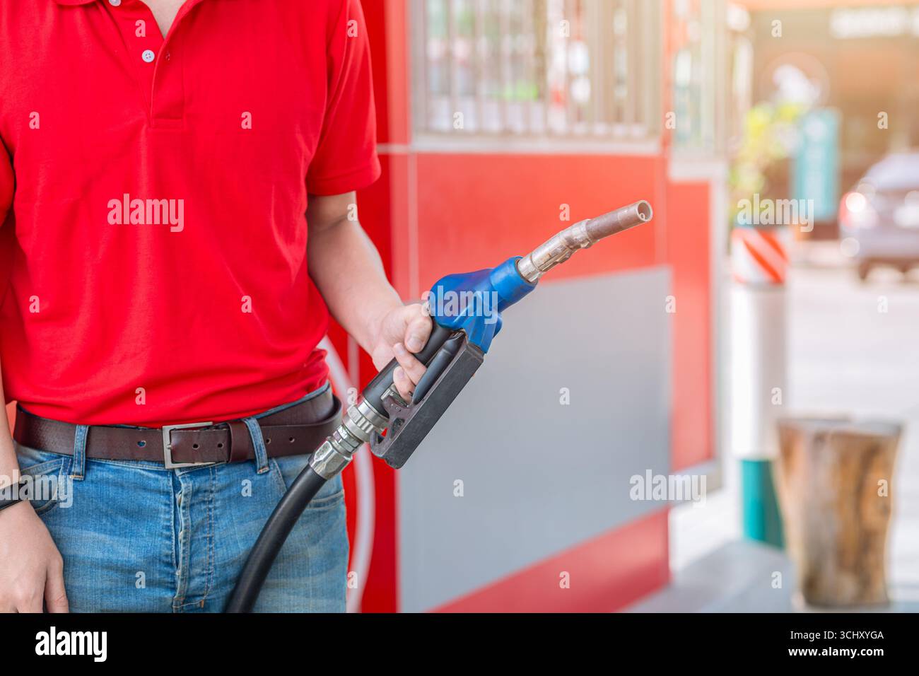 Primo piano operatore di una stazione di servizio che tiene a mano l'ugello del carburante per il rifornimento di carburante per auto, concetto di settore del mercato del petrolio Foto Stock