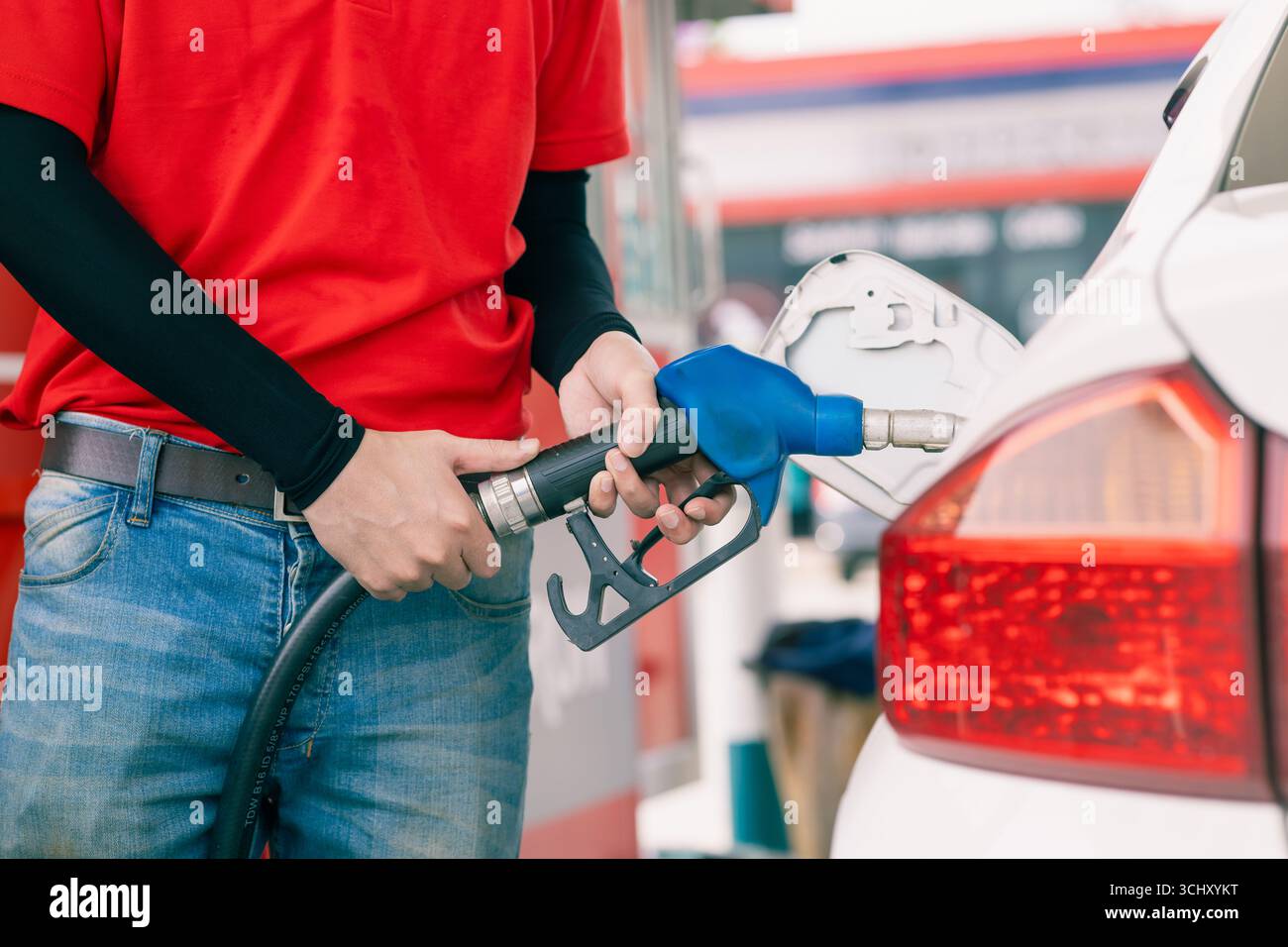 Primo piano operatore di una stazione di servizio che tiene a mano l'ugello del carburante per il rifornimento di carburante per auto, concetto di settore del mercato del petrolio Foto Stock