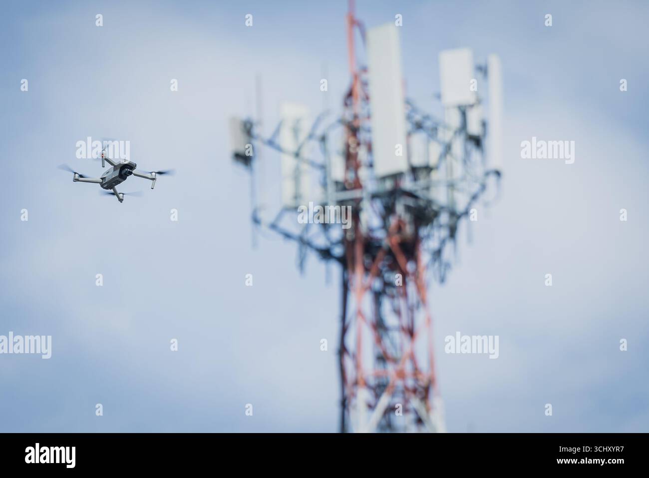 Drone UAV volare in cielo contro la torre di comunicazione per utilizzare la rete del sito cellulare per controllare a distanza il drone Foto Stock