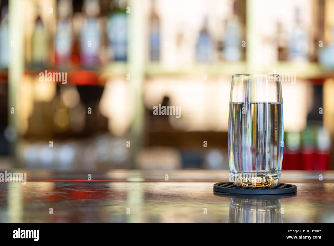 Un bicchiere d'acqua potabile, acqua pulita e pulita in vetro trasparente con sfondo sfocato a barra di lusso con spazio per il testo Foto Stock