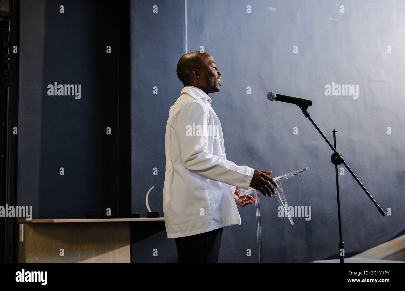 Presentando con fiducia alla conferenza, un uomo afroamericano che parla sul podio con microfono Foto Stock