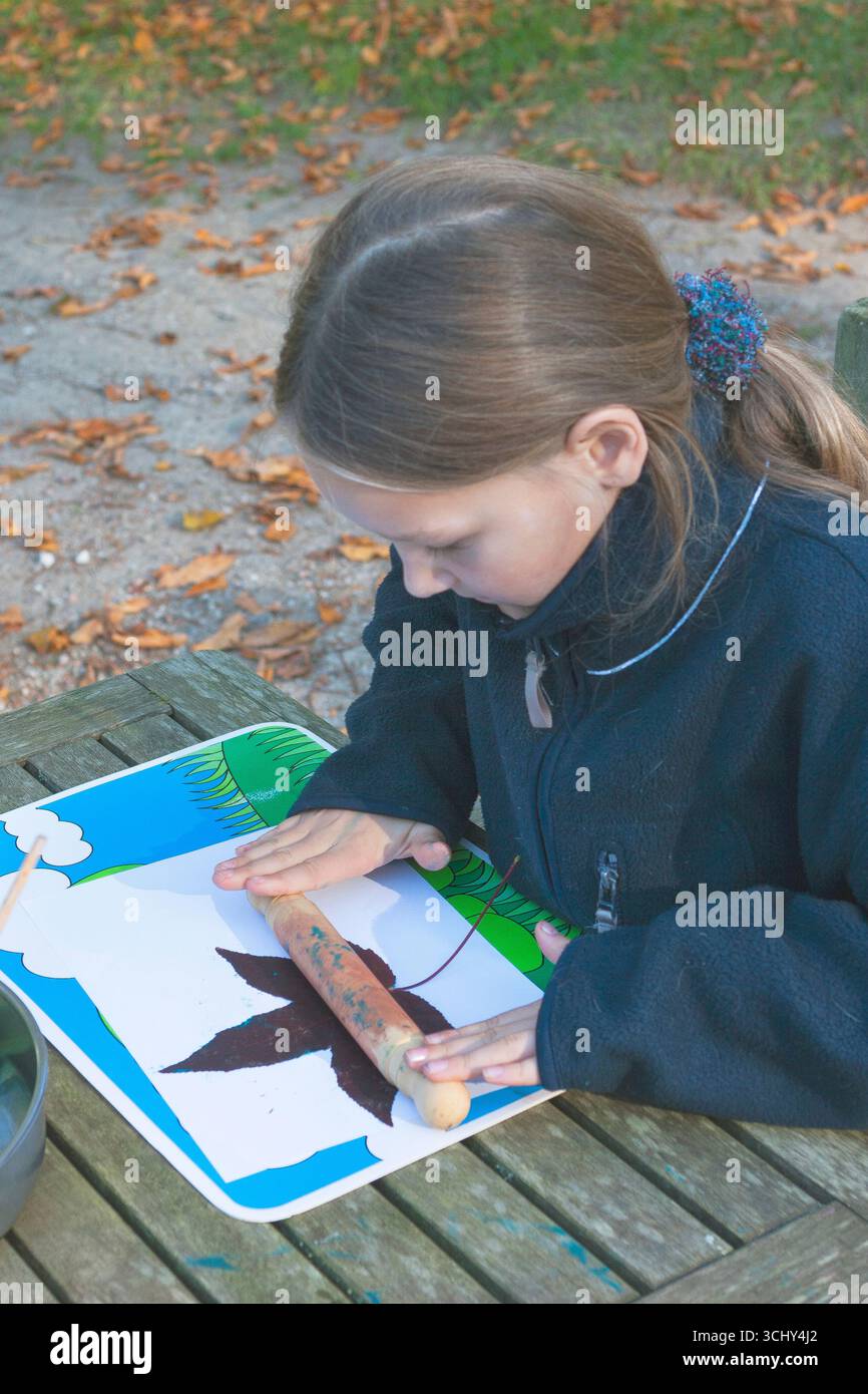 La ragazza che dipinge se ne va con l'inchiostro e li stampa su carta, stampa di foglie, Germania Foto Stock