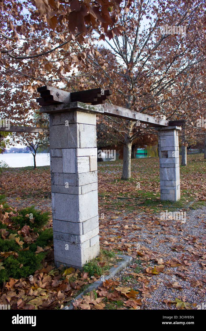 Colonne di pietra e struttura a travi di legno circondate da foglie d'autunno Foto Stock