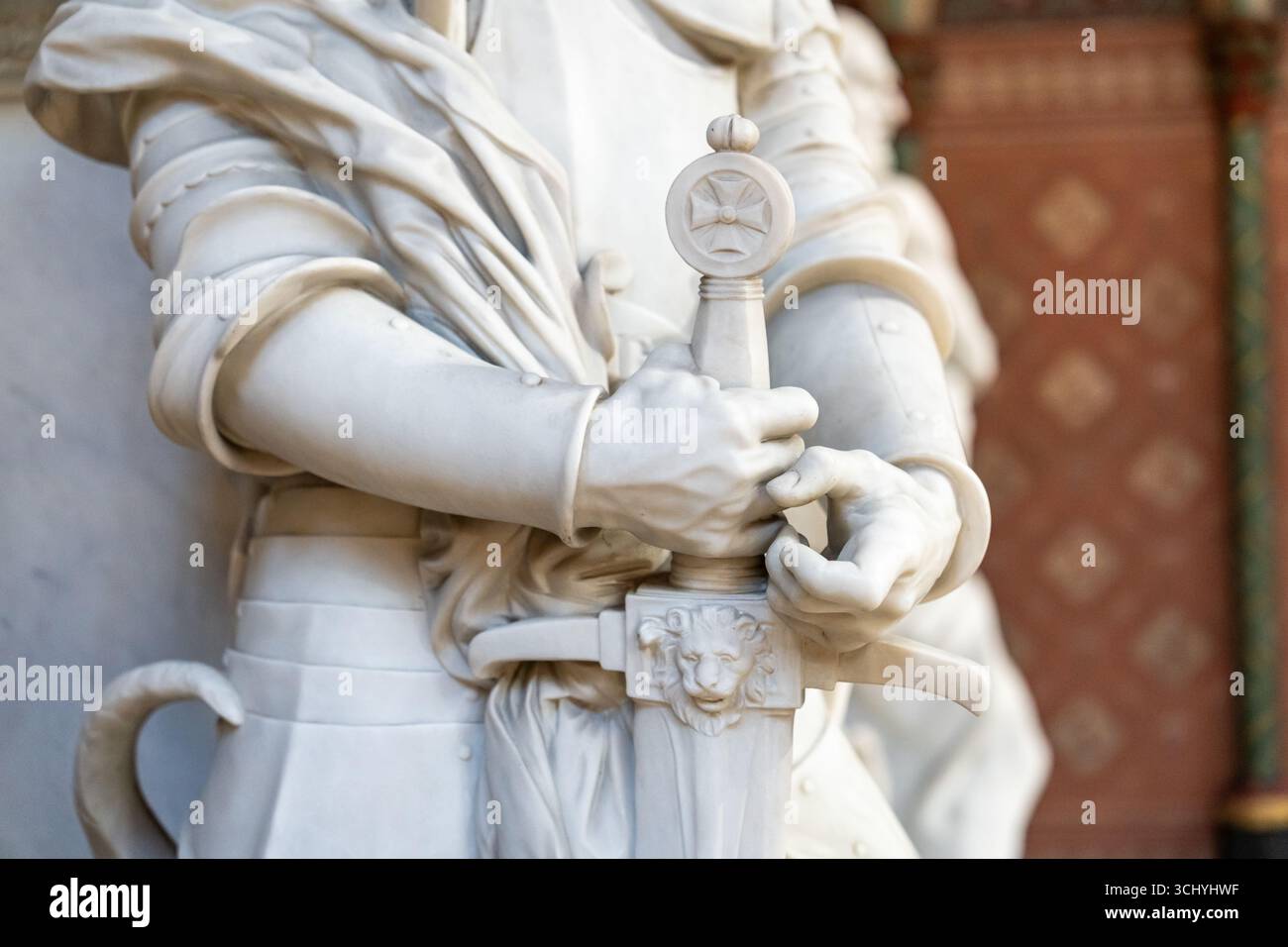 Primo piano su mani maschili con una spada di scultura in marmo che rappresenta un antico soldato crociato Foto Stock