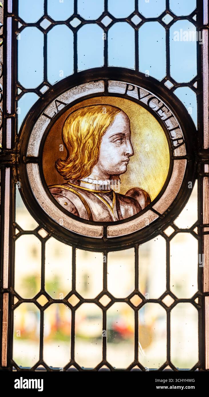 Primo piano su un profilo dipinto di una giovane bionda medievale che illustra la vetrata di un edificio storico in Francia Foto Stock