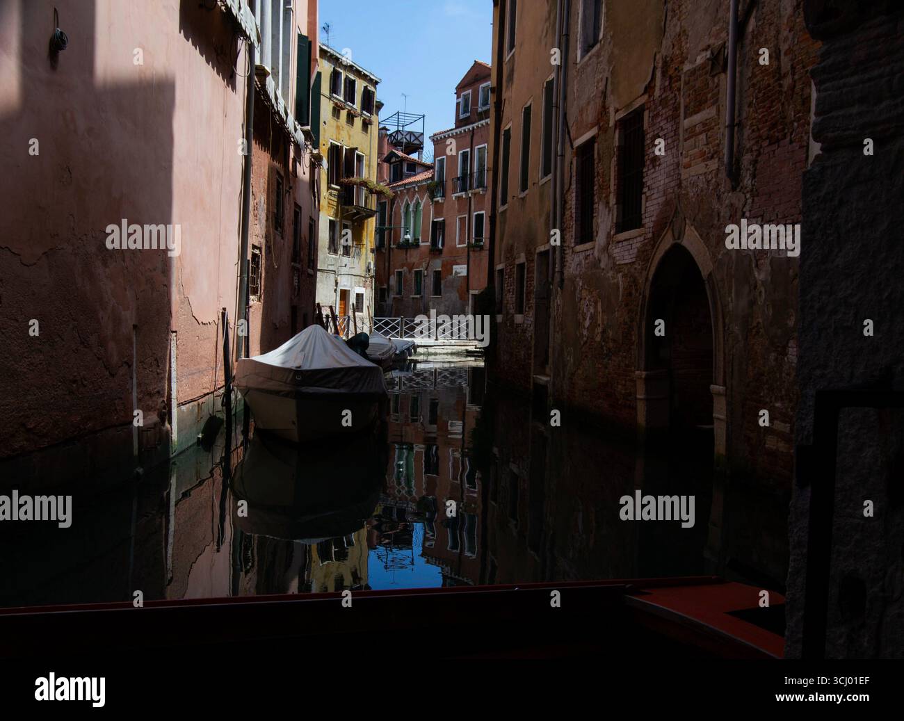 Un canale tratto da un vicolo tranquillo con acqua calmo e Una barca Foto Stock