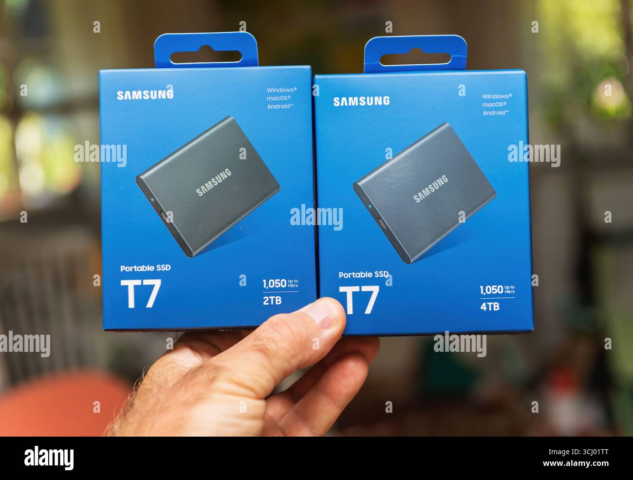 Parigi, Francia - 13 agosto 2025: Primo piano di due scatole Samsung Portable SSD T7 in mano, che mostrano capacità di storage di 2 TB e 4 TB, con confezione blu e dettagli del prodotto chiaramente visibili. Foto Stock