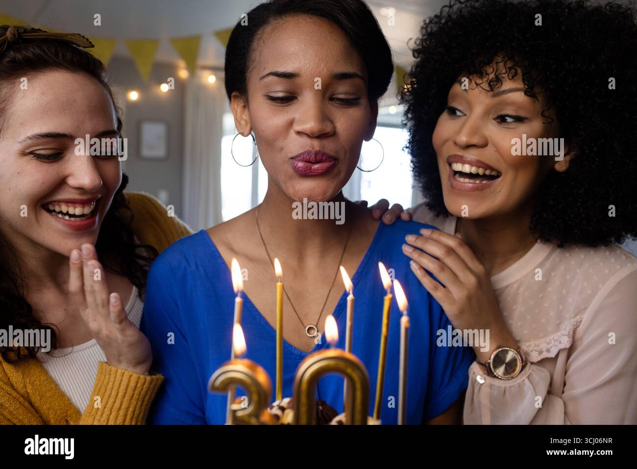 Diverse amiche femminili che celebrano il compleanno con torta, donna che fa desiderio, a casa Foto Stock