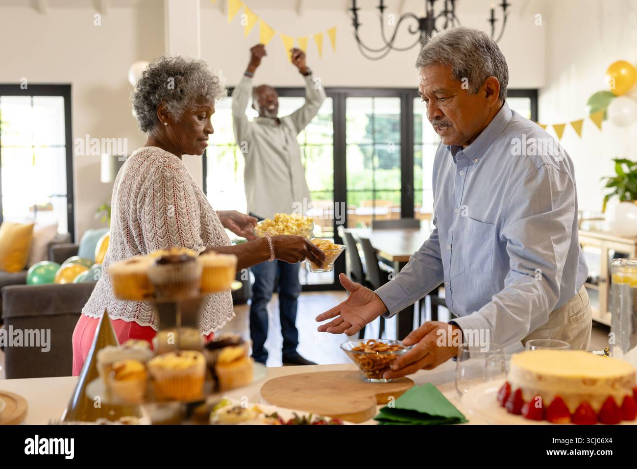 Coppie anziane che si godono spuntini durante le vivaci feste di casa con gli amici Foto Stock