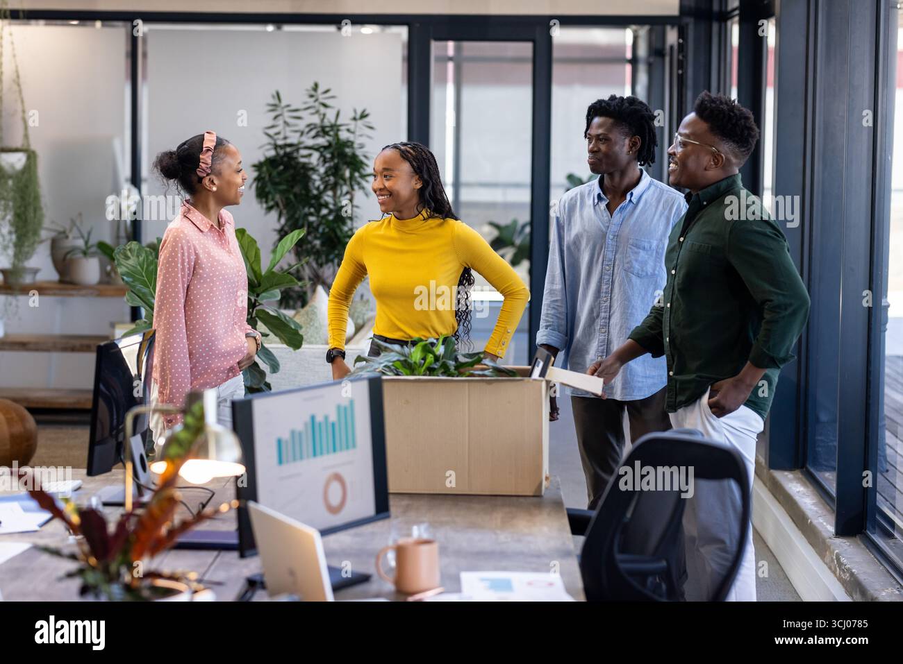 Team che discute nuove idee di progetto in un ufficio moderno, circondato da piante Foto Stock